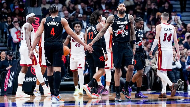Raptors players Brandon Ingram and Scottie Barnes exchange a low-five on the court during a playoff game