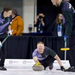 Curling skip delivering a stone during a competitive Rock League match