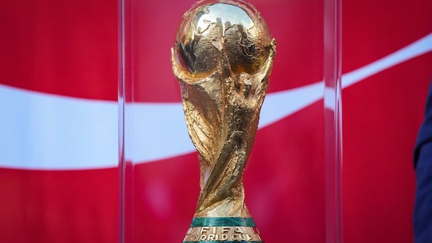 FIFA World Cup trophy displayed on a pedestal at the launch event in Vancouver with crowd gathered around