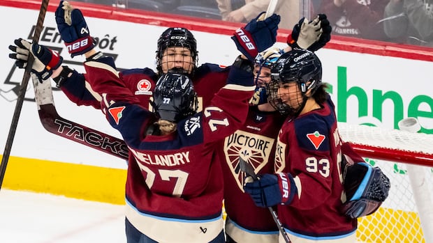 Victoire women's hockey players celebrate together in front of the net after their 10th home win of the season