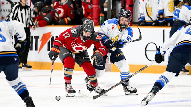 Three female hockey players embrace in the crease celebrating a key win in the PWHL playoffs