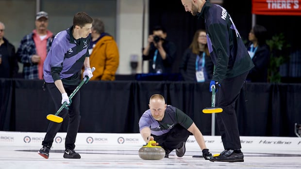 Curling skip releasing a stone during a match with focused teammates in the background
