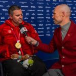Devin Heroux posing with a male wheelchair curling athlete holding a wheelchair curling broom on ice rink