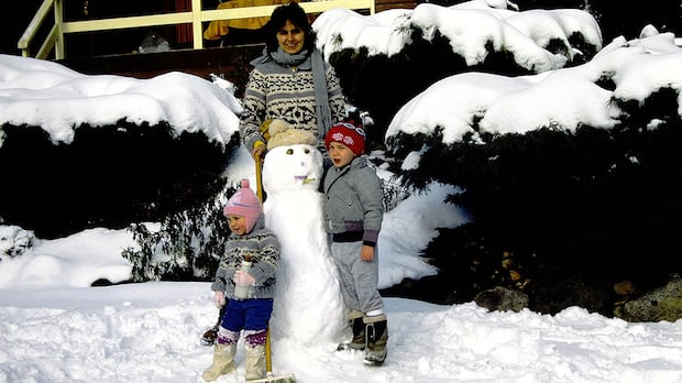 Young Christine Sinclair plays soccer in the snow with her mother and older brother