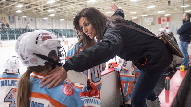 Manon Rhéaume speaks to a young hockey player on the bench during a hockey practice session