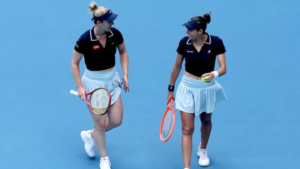 Canadian tennis players smiling and talking together on a blue court after winning women's doubles title