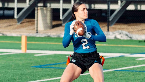 Female athlete running with American football in women's flag football game