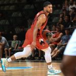 Players compete for the ball during an intense professional basketball game on a crowded indoor court