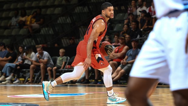 Players compete for the ball during an intense professional basketball game on a crowded indoor court