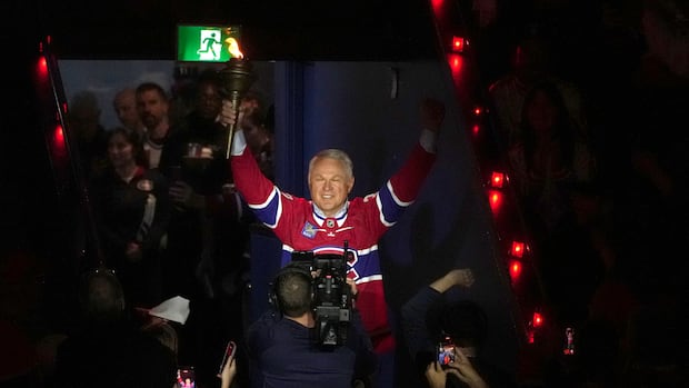 Claude Lemieux holding a torch during a hockey ceremony celebrating his career achievements