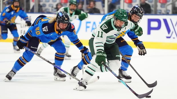 Female ice hockey player skating with puck while opponent closely defends during a game