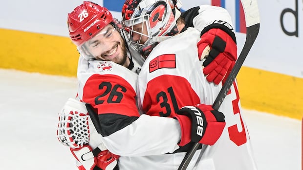 Hurricanes goalie making a save as Canadiens player tries to score during intense game action
