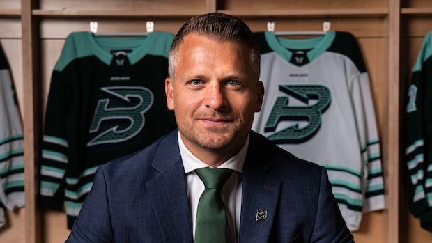 Kris Sparre in a suit looking at the camera during a hockey event announcement