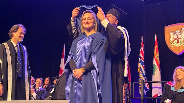 Marie-Philip Poulin in convocation robe receives honorary doctorate on stage at Bishop's University graduation ceremony