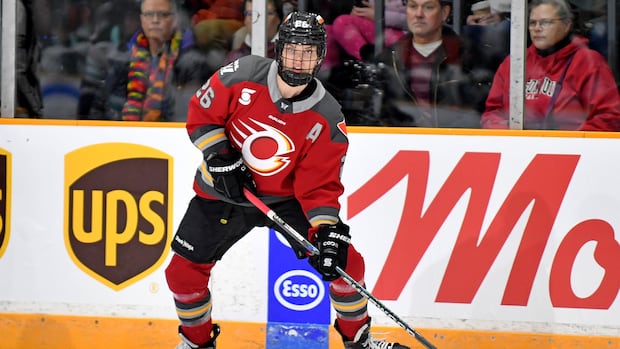 Emily Clark in a black hockey jersey skating during a game with the puck on the ice
