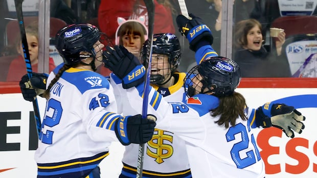 Three PWHL players celebrate during an intense game on the ice