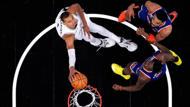 Top down view of basketball player attempting a shot against two defenders during intense NBA Finals game