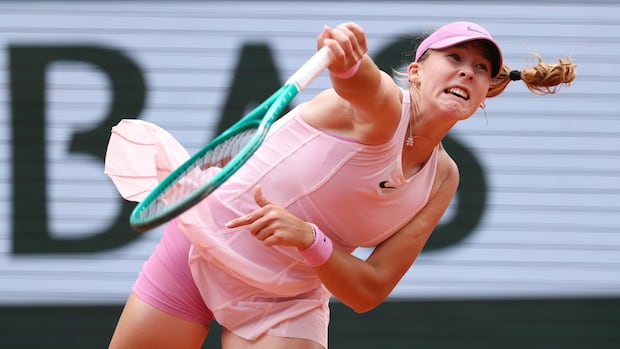 Mirra Andreeva in blue outfit serves during a tennis match at the French Open with intense focus